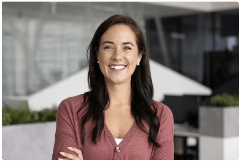 The AI interviewer, a smiling woman in a rose cardigan, on the main video tile